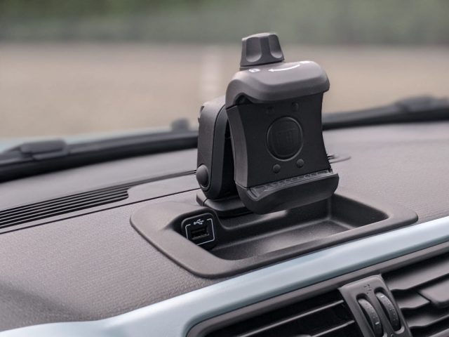 Een dashboardcamera gemonteerd op het dashboard van een Fiat Panda, met focus op de camera en een onscherpe achtergrond van het auto-interieur.