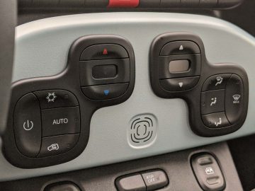 Auto-interieur van een Fiat Panda met bedieningselementen voor verlichting, spiegels en rijhulpfuncties op het bestuurdersdeurpaneel.