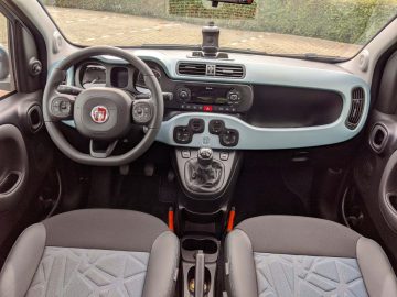 Binnenaanzicht van een Fiat Panda, met het stuur, het dashboard, de middenconsole en de stoffen stoelen.