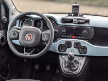 Binnenaanzicht van een Fiat Panda-auto met het stuur, het dashboard en de handmatige versnellingspook.