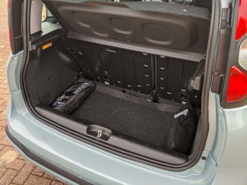 Open kofferbak van een Fiat Panda met een schoon interieur met een enkele zwarte plastic zak op de vloerbedekking.