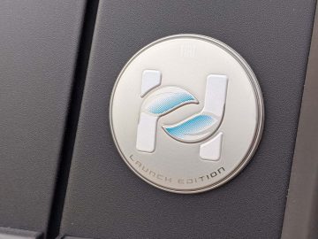 Close-up van een Fiat Panda-lanceringseditie-badge op het binnenpaneel van een auto, met een metalen logo met blauwe accenten.