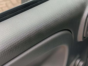 Close-up van het interieur van een Fiat Panda autodeur met getextureerd zwart plastic paneel.