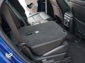 Een draagbare, met stof beklede koelbox, geplaatst op de achterbank van een moderne Ford Explorer PHEV met lederen interieur.