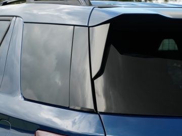 Close-up van een Ford Explorer PHEV, waarbij de nadruk ligt op de glanzende achterruit en een deel van het dak, wat het strakke ontwerp van de auto benadrukt.