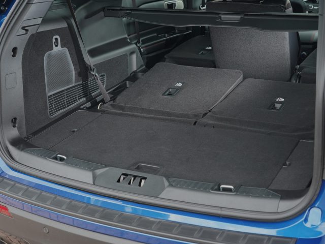 Open kofferbak van een Ford Explorer PHEV met plat neergeklapte achterbank om de laadruimte te maximaliseren, met een beschermende mat en een scheidingsrooster.