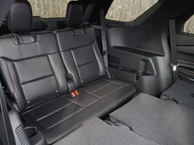 Binnenaanzicht van de achterbank van een Ford Explorer PHEV met zwart lederen bekleding en vloermatten met textuur.