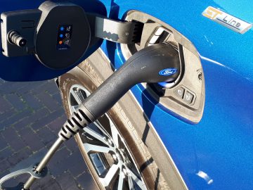 Oplaadkabel voor elektrische voertuigen aangesloten op de oplaadpoort van een blauwe Ford Explorer PHEV.