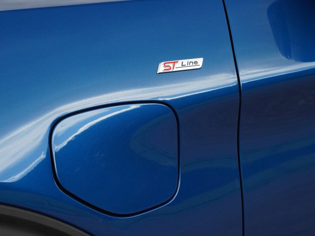 Close-up van een blauwe Ford Explorer PHEV met een "ST Line"-badge boven de tankdop.