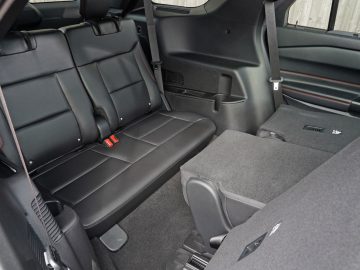 Binnenaanzicht van een Ford Explorer PHEV met zwartleren achterbank en grijze vloerbedekking.