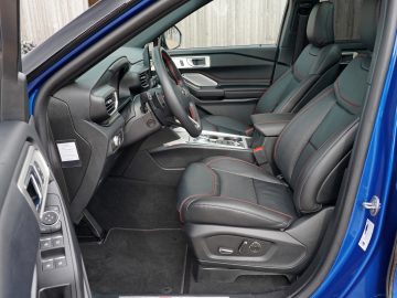 Binnenaanzicht van een Ford Explorer PHEV met zwartleren stoelen, een stuur en de middenconsole met metalen accenten.