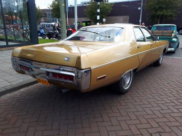 Een vintage gouden Chevrolet Impala, tentoongesteld tijdens de Saturday Night Cruise 2020, die buiten geparkeerd staat en het ontwerp van de achterkant en klassieke stijlelementen laat zien.