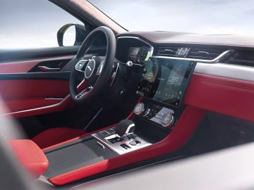 Interieur van een Jaguar F-Pace met een rood en zwart lederen dashboard, voorzien van een stuur en een digitaal beeldscherm.
