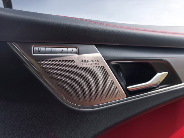 Close-up van het interieur van een Jaguar F-Pace-autodeur met een meridiaan surround sound-luidsprekersysteem, met een metalen afwerking en bedieningsknoppen genummerd 1 tot 3.