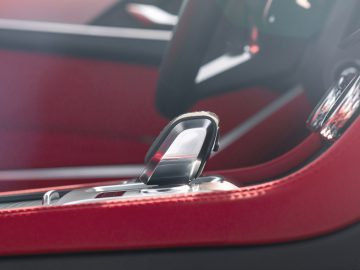 Close-up van het rode luxe interieur van een Jaguar F-Pace met een gedetailleerd zicht op de versnellingspook en lederen stiksels.