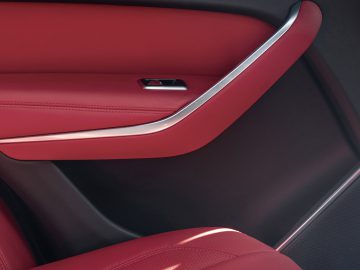 Binnenaanzicht van de Jaguar F-Pace met elegante roodleren bekleding en koolstofvezelaccenten.