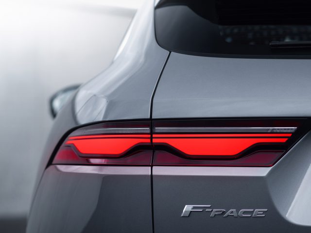 Close-up van het achter- en achterlicht van een grijze Jaguar F-Pace SUV, met de nadruk op het strakke ontwerp en de modelnaam.