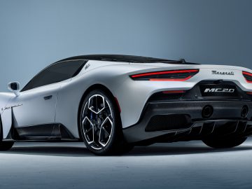 Een zilveren Maserati MC20-sportwagen, gezien vanaf de achterkant tegen een grijze achtergrond.