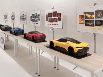 Een tentoonstellingsdisplay met verschillende automodellen, waaronder de Maserati Grecale, en posters met designconcepten aan de muur.