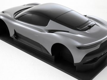 Een schaalmodel van een futuristische zilveren Maserati Grecale, weergegeven op een zwart platform, met een strak ontwerp en aerodynamische kenmerken.
