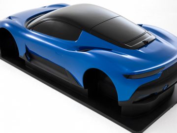 Een strakke blauwe conceptsportwagen van Maserati Grecale, tentoongesteld op een wit platform, met futuristische ontwerpkenmerken en aerodynamische carrosserievorm.