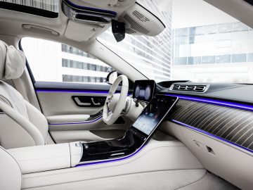 Binnenaanzicht van een Mercedes-Benz S-Klasse met een luxueus ontwerp met lederen stoelen, digitaal dashboard en sfeerverlichting.