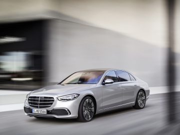 Een zilveren Mercedes-Benz S-Klasse sedan in beweging door een stadsstraat, met dynamisch design en moderne elegantie.