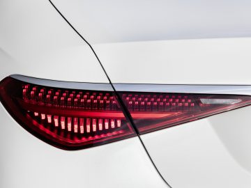 Close-up van een rood achterlicht van de Mercedes-Benz S-Klasse op een witte carrosserie, met ingewikkelde LED-details.