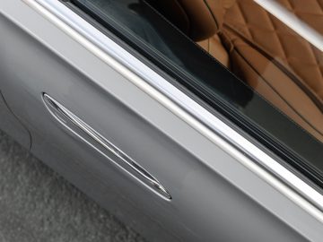 Close-up van de deurklink van een auto op een zilveren Mercedes-Benz S-Klasse met een glimp van een bruinleren interieur.