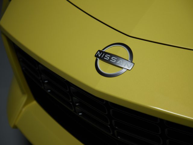 Close-up van de grille en het embleem van een gele Nissan Z Proto-auto.