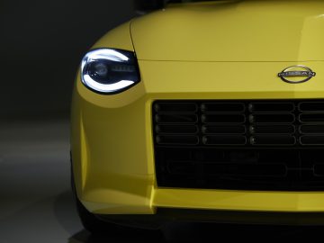 Close-up van een gele Nissan Z Proto, gericht op de koplamp en de grille.
