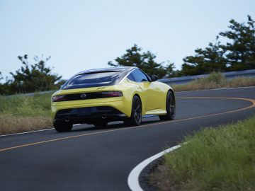 Een gele Nissan Z Proto-sportwagen die op een bochtige bergweg rijdt.