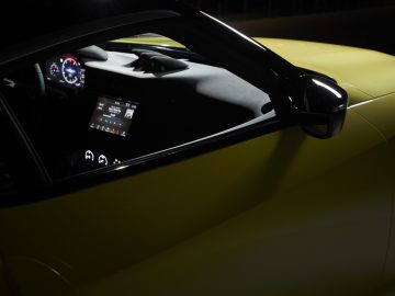 Nissan Z Proto-sportwagen waarvan het interieur verlicht is, waardoor het stuur en het dashboard benadrukt worden, 's nachts van buitenaf gezien door het zijraam aan de bestuurderszijde.