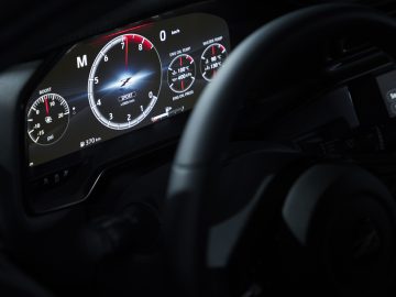 Close-up van het dashboard van een Nissan Z Proto-auto met verlichte snelheidsmeter en toerenteller, gezien van achter het stuur.