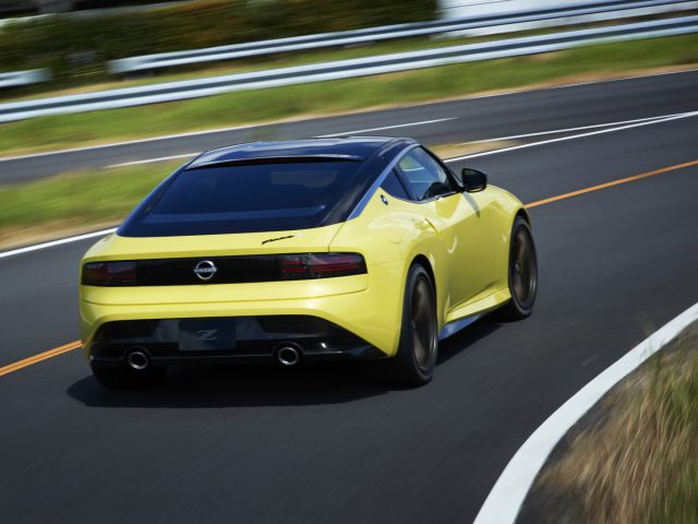 Een gele Nissan Z Proto-sportwagen snelt over een snelweg, in beweging weergegeven met vage lijnen op de weg.