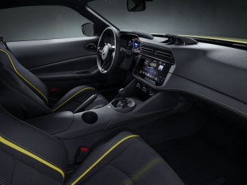 Binnenaanzicht van de Nissan Z Proto met een stuur, digitaal dashboard, handgeschakelde versnellingsbak en tweekleurige stoelen met gele stiksels.