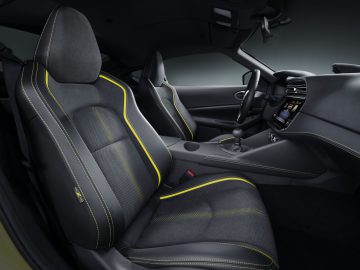 Binnenaanzicht van de Nissan Z Proto met de bestuurdersstoel en het dashboard met gele accentstiksels.