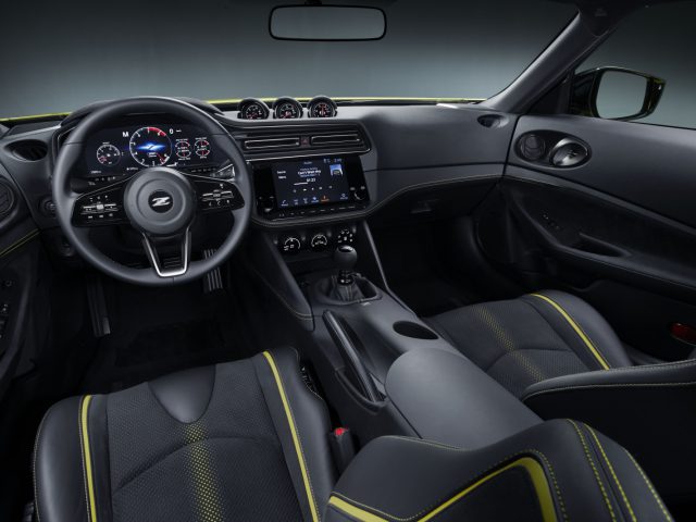 Binnenaanzicht van de Nissan Z Proto met strak dashboard, leren stoelen met gele stiksels en digitale displays.