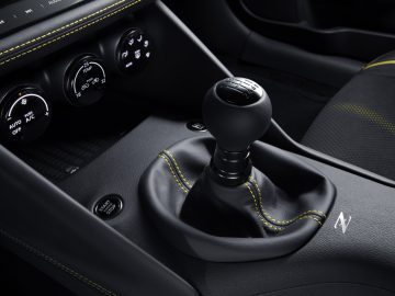 Binnenaanzicht van een Nissan Z Proto-auto met een handgeschakelde versnellingspook met zwarte en gele stiksels.