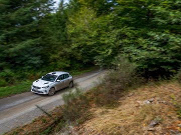 Opel Corsa Rally4 rijdt over een bochtige bosweg, waarbij bewegingsonscherpte beweging overbrengt.