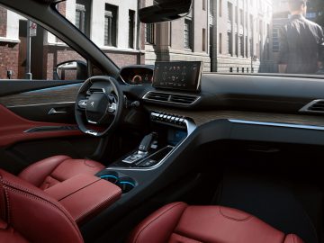 Binnenaanzicht van de Peugeot 3008 met roodleren stoelen en een strak dashboard, voorzien van een groot touchscreen en digitale bediening.