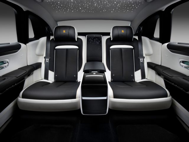 Interieur van een Rolls-Royce Ghost met vier stoelen die face-to-face zijn opgesteld, met een hemelbekleding in sterrenlicht en hoogwaardige afwerking.