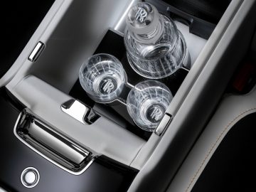 Luxe Rolls-Royce Ghost-interieur met een middenconsole met een open compartiment met daarin een op maat gemaakte kristallen karaf en glazen set, voorzien van het Rolls-Royce-logo in reliëf.