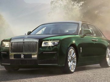 Een donkergroene Rolls-Royce Ghost geparkeerd op een weg waar het zonlicht door de bomen schijnt en het gepolijste exterieur en de glanzende grille van de auto benadrukt.