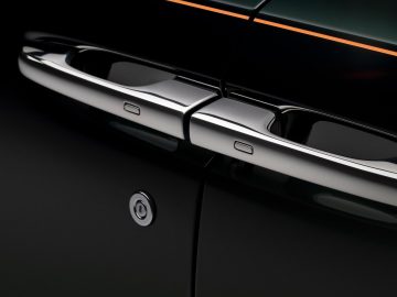Close-up van de zijkant van een zwarte Rolls-Royce Ghost met glanzend verchroomde deurgrepen en sleutelgat, wat een strak en modern ontwerp benadrukt.