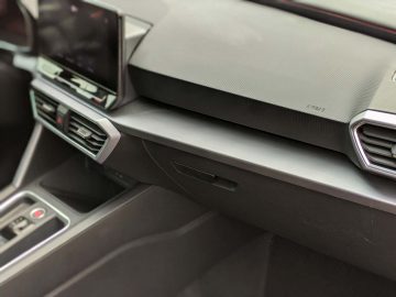 Close-up van het dashboard van een Seat Leon Sportstourer met ventilatieopeningen, een multimediascherm en gestructureerde panelen.