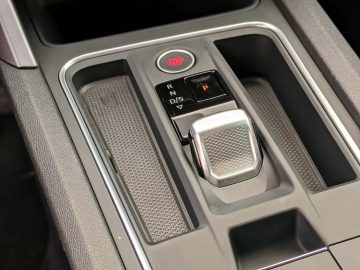 Een close-up van de moderne versnellingspook van een Seat Leon Sportstourer met elektronische shift-by-wire-transmissie, met parkeer-, achteruit-, neutraal- en rijopties.