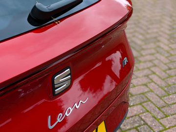 Achteraanzicht van een rode Seat Leon Sportstourer met het logo, de modelnaam en een kleine spoiler.