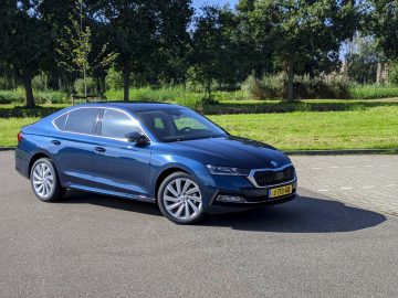 Blauwe Skoda Octavia geparkeerd op een verhard terrein vlakbij een grasveld, gezien bij daglicht.