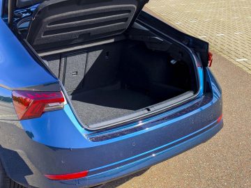 Blauwe Skoda Octavia met een open kofferbak, met een schoon en leeg interieur, geparkeerd op een zonnige dag.